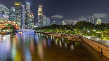 Singapur gökdelenleri beyaz Anderson Köprüsü ve Escplanade Park yakınlarındaki birkaç finans bölgesi kulesi ile gökdelenden geceye geçiş zamanı. Her iki tarafta da yeşil yapraklar var..