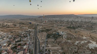 Sıcak hava balonundan gelen hava manzarası diğer uçan balonlarla birlikte Kapadokya 'nın peri masalı manzarası tepelerinin üzerinden geçiyor. Goreme, Kapadokya, Türkiye