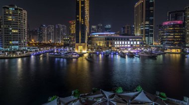 Alışveriş merkezi, restoranlar, kuleler ve yatlarla Dubai Marina 'nın hava görüntüsü. Günbegün geçiş zamanı, Birleşik Arap Emirlikleri. Gün batımından sonra kanalın üst görüntüsü