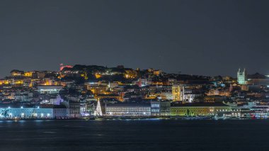 Lizbon Ticaret Meydanı 'nın zaman çizelgesi Noel için aydınlatıldı. Turistler, açılış ışık gösterisi sırasında parlayan ağacın ve dekorasyonların etrafında toplanıyorlar. Portekiz 'in başkentinde gece sahnesi