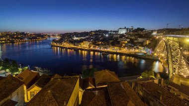 Panorama old city Porto at river Duoro, with Port transporting boats day to night transition timelapse with the Arrabida bridge after sunset, Oporto, Portugal