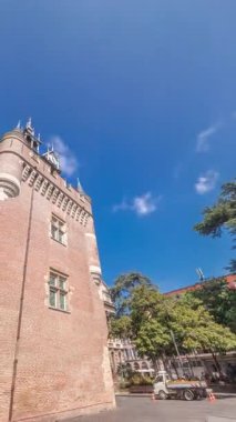 Rönesans zindan saat kulesi ve Capitole zaman atlamasının klasik tuğla cephesi Fransa 'nın Toulouse belediyesi mavi bulutlu gökyüzünün altında Charles de Gaulle Meydanı' nda ağaçlarla çevrili.