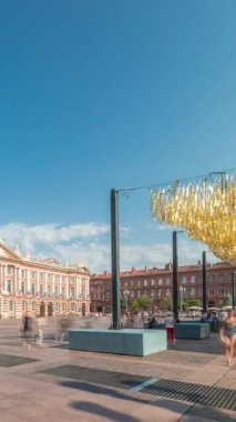 Capitole de Toulouse zaman çizelgesini gösteren panorama, Fransa 'nın Toulouse şehrinin tarihi belediye binasını ve belediye merkezini gösteriyor. Capitole Meydanı' nda mavi bulutlu gökyüzü altında birçok restoran bulunuyor.