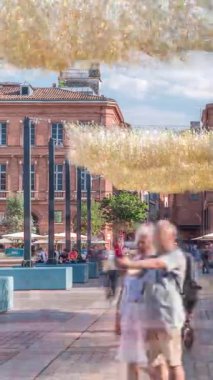 Fransa 'nın Toulouse şehrinde Capitole Meydanı' nda. İkonik kırmızı tuğlalı tarihi ön cephelerde açık hava kafeleri, beyaz şemsiyeler ve süslemeli ışıklandırmalar var. Canlı bir yaya istikameti.