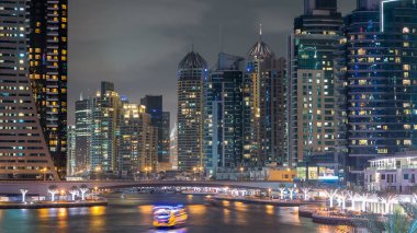 Dubai Marina rıhtımı, Dubai 'deki köprüden gece vardiyasına kadar uzanan kuleleri ve yatları olan Birleşik Arap Emirlikleri. Çevresinde yapay kanallar ve aydınlık gökdelenler olan bir bölge.