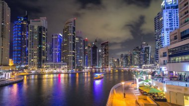 Dubai Marina rıhtımı, Dubai 'deki köprüden gece vardiyasına kadar uzanan kuleleri ve yatları olan Birleşik Arap Emirlikleri. Yapay kanalları ve gökdelenleri olan bir bölge.