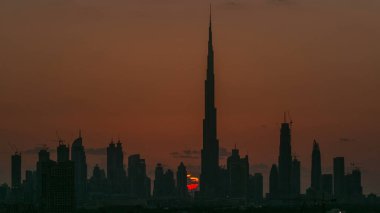 Akşam saatlerinde Dubai şehir merkezinin ufuk çizgisi ile gün batımı. Çölde inşa edilmiş modern gökdelenlerin güzel gökdelenleri. Havaalanı yakınındaki binadan hava görüntüsü
