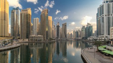 Dubai Marina Kanalı, modern kuleleri ve yatları olan liman kenti Dubai 'deki köprüden gece gündüz geçiş zamanı olan Birleşik Arap Emirlikleri' ne yansıyor. Güneş doğmadan önce etraftaki gökdelenler