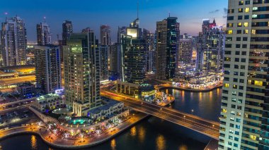 Dubai Marina gezinti güvertesi ve kanalı, gün batımından sonra Dubai, BAE 'de yüzen yat ve tekneler ile gündüz hava manzaralı. Modern kuleler, köprü ve trafik yukarıdan geliyor.
