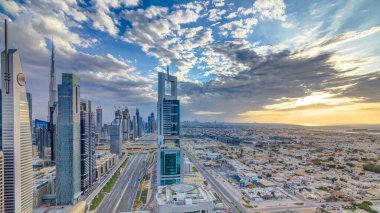 Dubai gökdelenleri, gün batımı akşam vakti. Dubai metro istasyonu ve Şeyh Zayed Yolu 'ndaki trafik. Kule çatısından gökyüzü görüntüsü. Güzel renkli bulutlu gökyüzü ve güneş ışığı