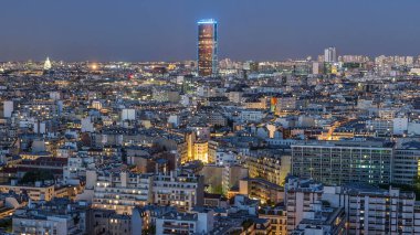 Paris 'teki evlerin çatılarının üstündeki hava panoraması gece gündüz geçiş zamanı. Günbatımından sonra aydınlatılan ana manzaralarla akşam manzarası