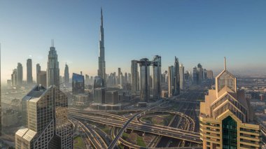 Dubai şehir merkezi silueti en yüksek gökdelenler ve karayolu kavşak gece gündüz geçiş timelapse üzerinde en işlek trafik ile. Yukarıdan havadan görünüm