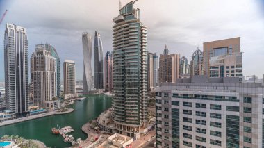 Dubai Marina yerleşim ve ofis gökdelenlerinin deniz manzarası. Yüzen tekneler ve yatlar. Sabah bulutlu bir gökyüzü