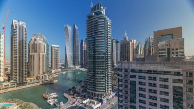 Dubai Marina yerleşim ve ofis gökdelenlerinin deniz manzarası. Gün doğumundan sonraki sabah gölgeler hızla hareket ediyor. Güneş camdan yansıyor. Yüzen tekneler ve yatlar