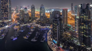 Dubai Marina'nın havadan üstten gündüz geceye geçiş saati. Dubai, Bae gün batımından sonra yüzen yatlar ve tekneler ile gezinti ve kanal. Işıklı modern kuleler ve yolda trafik