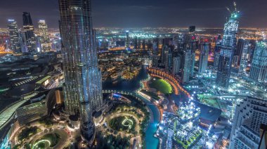 Dubai şehir merkezindeki panoramik gökyüzü manzarası, alışveriş merkezi, çeşmeler ve Burj Khalifa 'nın hava gece zaman çizelgesi. Günbatımından sonra modern gökdelenler ve bulutlu gökyüzü