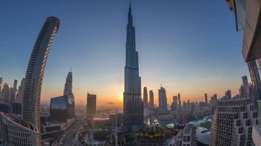 Gün doğmadan Dubai şehir merkezindeki panoramik gökyüzü manzarası alışveriş merkezleri, çeşmeler ve Burç Halife hava durumu geçiş zamanı. Modern gökdelenler ve inşaat alanı