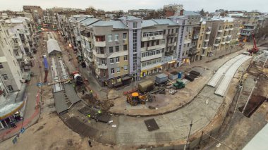 Beton yol yapımında çok sayıda işçi ve mikser makinesi, vinç, traktör zaman ayarlı çalışır. Tramvay raylarının yeniden inşası. Yukarıdan tüm gün boyunca gökyüzü görüntüsü