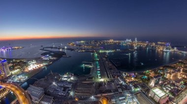 Palm Jumeirah Adası gün gece geçiş timelapse için hava gün batımı manzarası. Üstten görünüm ışıklı Villaları, otelleri ve yatlar ile akşam. Yeni cruise terminal inşaat süreci