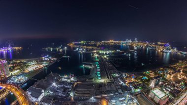 Palm Jumeirah Adası gün gece geçiş timelapse için hava gün batımı manzarası. Üstten görünüm ışıklı Villaları, otelleri ve yatlar ile akşam. Yeni cruise terminal inşaat süreci