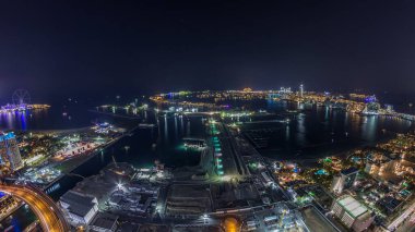 Palm Jumeirah Adası gün gece geçiş timelapse için hava gün batımı manzarası. Üstten görünüm ışıklı Villaları, otelleri ve yatlar ile akşam. Yeni cruise terminal inşaat süreci