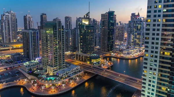 Dubai Marina gezinti güvertesi ve kanalı, gün batımından sonra Dubai, BAE 'de yüzen yat ve tekneler ile gündüz hava manzaralı. Modern kuleler, köprü ve trafik yukarıdan geliyor.