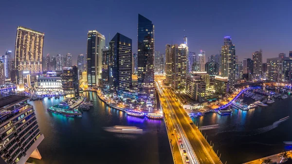 Dubai Marina gezinti güvertesi ve kanalı, gün batımından sonra Dubai, BAE 'de yüzen yat ve teknelerle panoramik hava manzaralı. Modern kuleler ve yoldaki trafik.