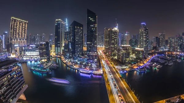 Dubai Marina gezinti güvertesi ve kanalı, gün batımından sonra Dubai, BAE 'de yüzen yat ve teknelerle panoramik hava manzaralı. Modern kuleler ve yoldaki trafik.