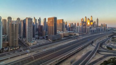 Dubai Yat Limanı gökdelenler hava üstten görünüm sabah Jlt günbatımı içinde Dubai timelapse, Birleşik Arap Emirlikleri için gün boyunca. Modern kule uzun gölgeler aşağıya taşınması ve Şeyh zayed yolu üzerinde trafik ile.