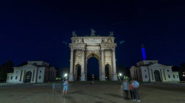 Piazza Sempione 'deki Arco della Pace (Simplon Meydanı' ndaki Barış Kemeri), panoramik geçiş zamanına göre gündüzden geceye. Akşam aydınlatması. Bu neoklasik bir zafer kemeri.