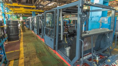 Konveyör montajı, traktörün gövdesini büyük endüstriyel fabrika zaman diliminde sahneleyecek. Kabin montajı, kurulum parçaları özel bir masada.