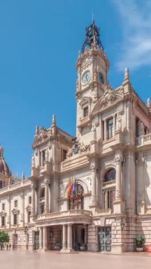 Valencia Belediye Binası Ajuntament de Valencia zaman atlaması Plaza de Ayuntamiento 'da. Mavi gökyüzünün altında saat kulesi olan tarihi bir bina. İspanya 'nın ana meydanında gezinen insanlar