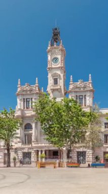 Valencia Belediye Binası Ajuntament de Valencia zaman atlaması Plaza de Ayuntamiento 'da. Mavi bulutlu gökyüzünün altında saat kulesi olan tarihi bir bina. İspanya 'nın ana meydanında gezinen insanlar
