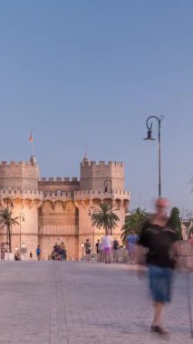 Serrans Kuleleri Torres de Serranos günden geceye Valencia, İspanya 'daki geçiş zamanı. Şehrin antik duvarlarından gelen büyük bir ortaçağ kapısı. İnsanlar tarihi bir yere yakın bir köprüde yürüyorlar.