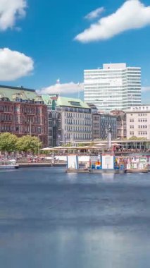 Almanya, Hamburg 'daki Binnenalster zaman ölçümüne bakın. Alster Gölü 'nün iç sularına yansıyan tarihi binalar mavi gökyüzünün altında. Gemili ve rıhtımlı manzaralı şehir manzarası