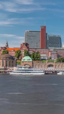 St.Pauli Piers Landungsbrucken 'de Hamburg, Almanya' da feribotlu Skyline zaman çizelgesi. İkonik saat kulesi, yat limanına yanaşan gemiler ve bulutlu mavi gökyüzünün altındaki limanın panoramik manzarası.