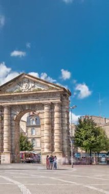 Fransa, Bordeaux 'da Place de la Victoire' da Porte dAquitaine kemeri ve dikilitaş. Tramvay hatları, kafeler ve mavi bulutlu gökyüzünün altında çevreleyen canlı Bordeaux 'nun tarihi simgesi.