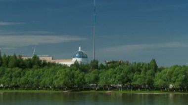 nehir Ishim timelapse, Bina, Bina, tratuar ve park ağaçlarda. Güneşli bir gün. Astana, Kazakistan