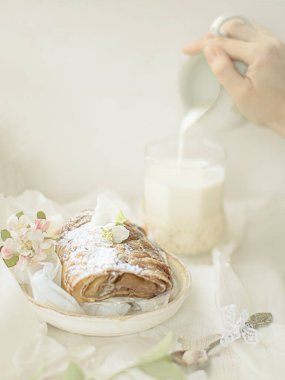 Beyaz bir tabakta çörek ve bir bardak süt.