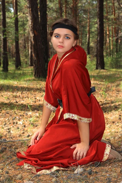 Glade çam bir çam ormanının içinde üzerinde Kırmızı elbiseli kız