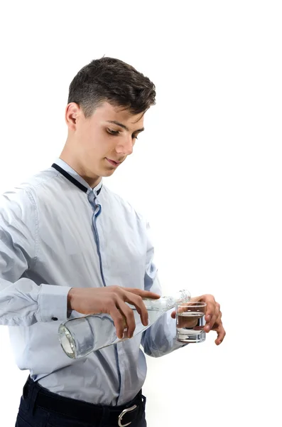 Hombre adolescente camarero vertiendo agua de la botella de vidrio en un vaso — Foto de Stock