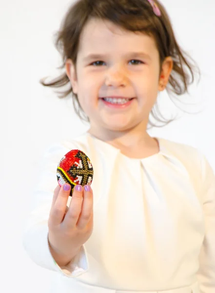 Süßes kleines Mädchen hält ein Osterei in der Hand, das isoliert auf weiß gemalt ist — Stockfoto