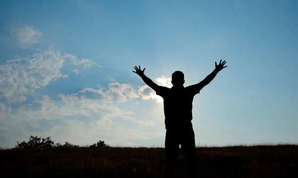 Silhueta do homem adoração com as mãos levantadas para o céu na natureza — Fotografia de Stock