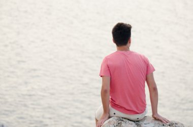 Genç melankolik oturmak sırt üstünde tepe-in büyük taş seyir ile bir