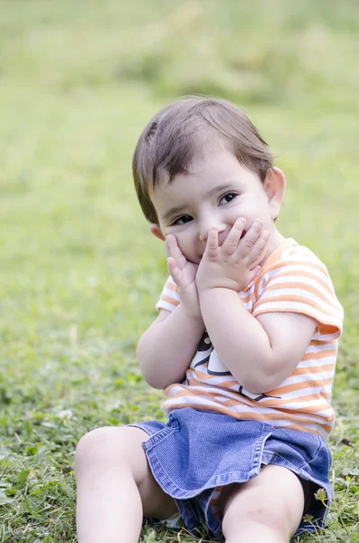 Счастливый ребенок, сидящий на траве — стоковое фото