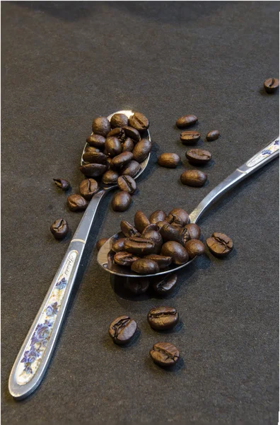 Café frijoles en cucharas sobre negro — Foto de Stock