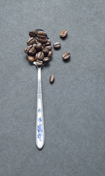 Grãos de café em colher isolados em preto — Fotografia de Stock