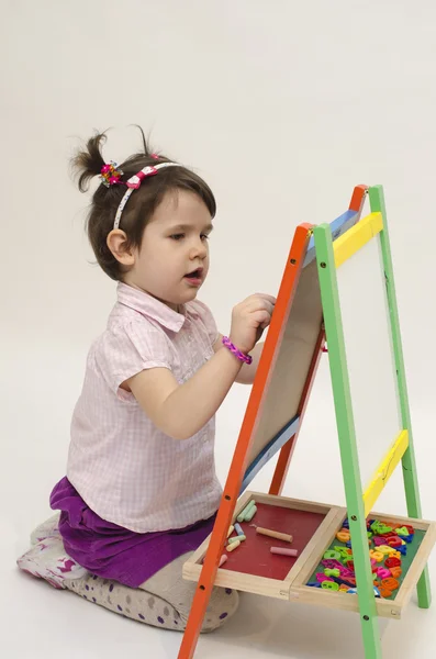 Adorabile bambina disegnare su lavagna nera con gesso — Foto Stock