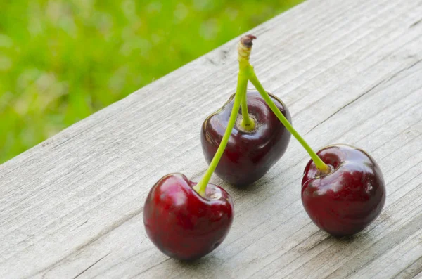 3 Cherries on wooden background — Stock Photo, Image