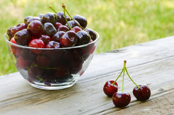 Cherries in bowl and on wood — Stock Photo, Image